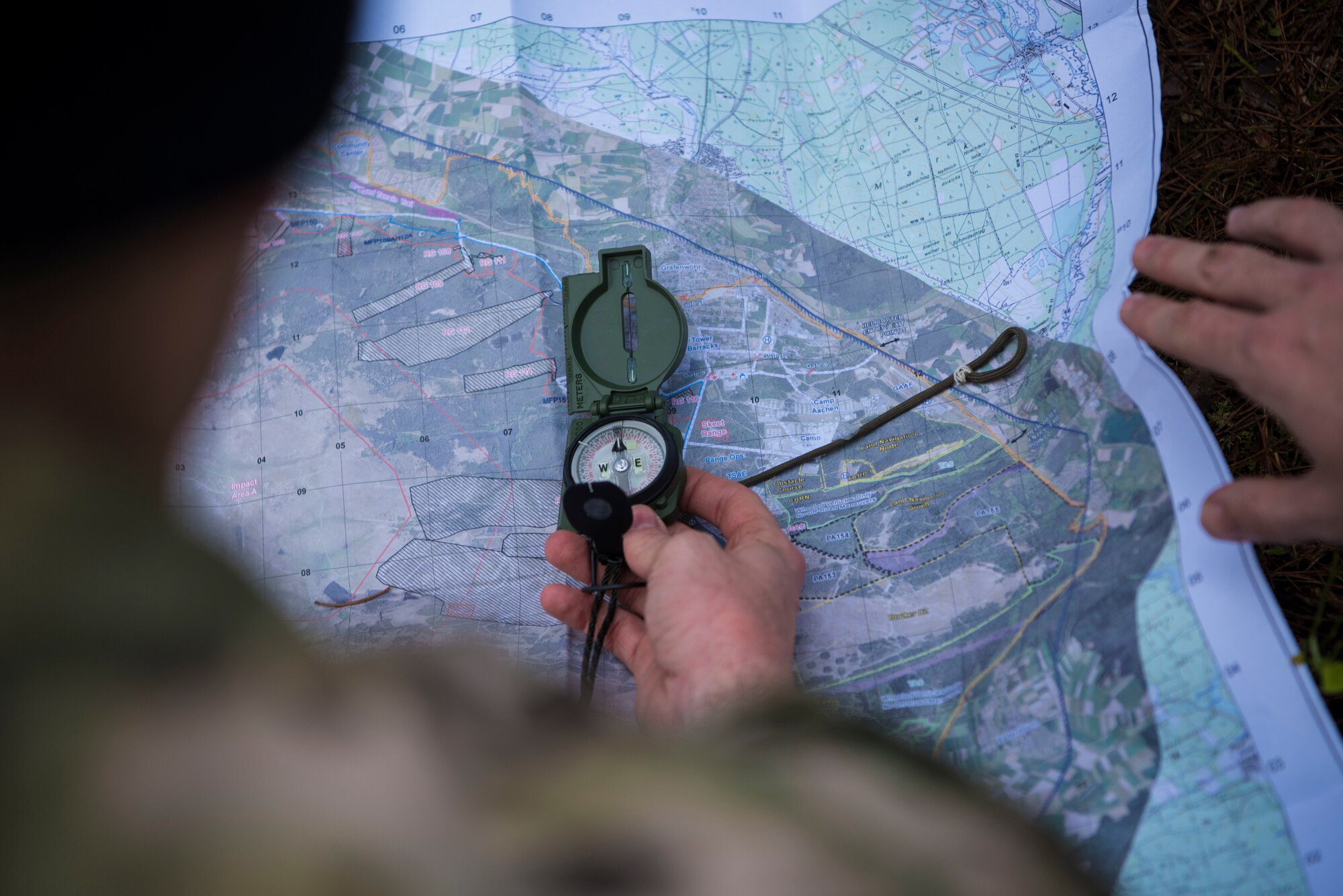 U.S. Air Force Staff Sgt. Ryan Silva, 435th Security Forces Squadron contingency response member, holds a compass against a map while participating in a Survival Evasion Resistance Escape navigation course during exercise Agile Wolf 21-01.