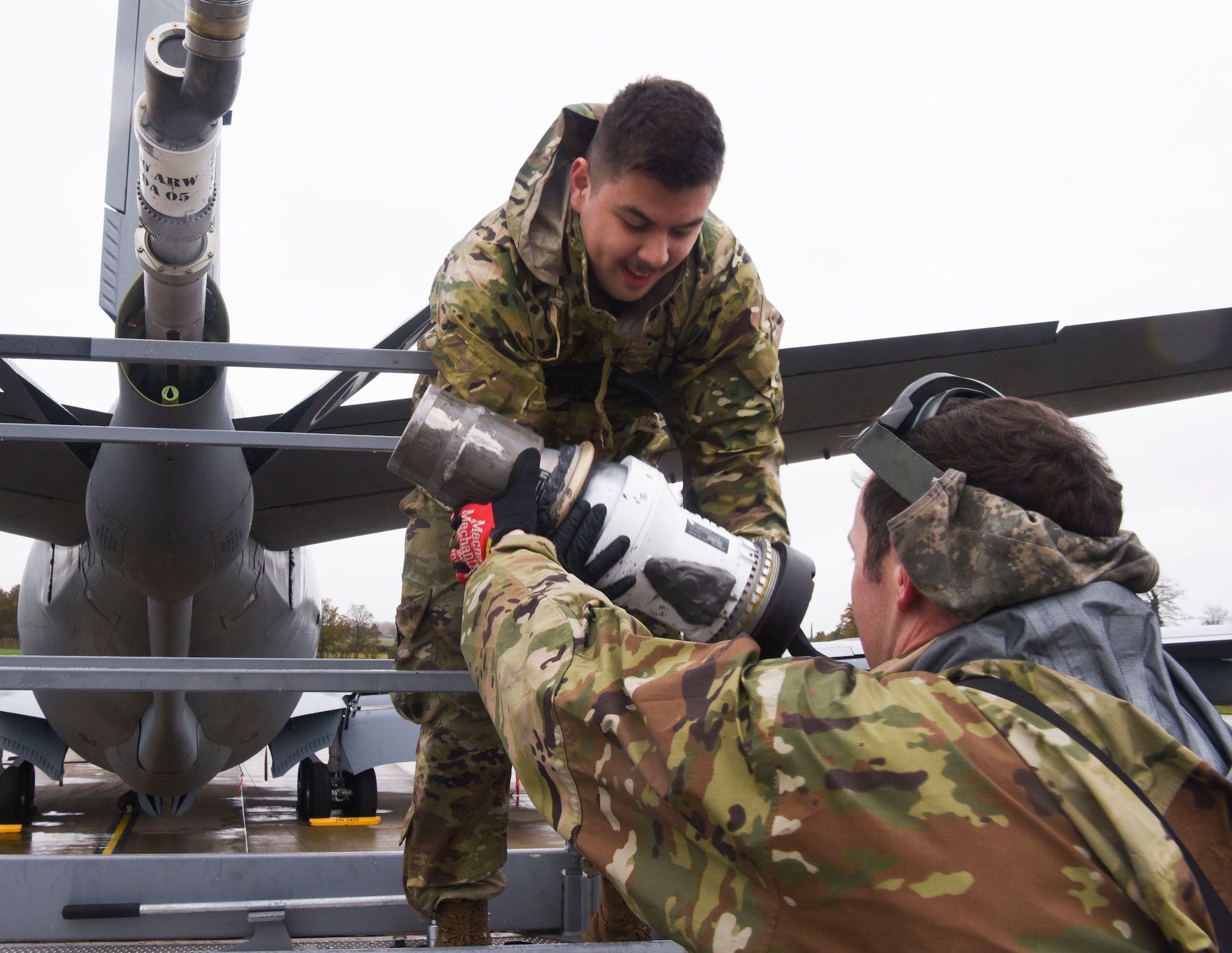 U.S. Air Force Staff Sgt. Elijah Ward, right, 100th Aircraft Maintenance Squadron crew chief, passes the boom nozzle to Airman 1st Class Julian Nailing, left, 100th AMXS crew chief, to attach to a KC-135 Stratotanker aircraft for refueling operations at Royal Air Force Mildenhall, England, Oct. 29, 2020. Standing on a platform level to the boom, the two crew chiefs will replace the drogue with the boom nozzle, which will allow the drogue to be taken away for maintenance. (U.S. Air Force photo by Airman 1st Class David Busby)