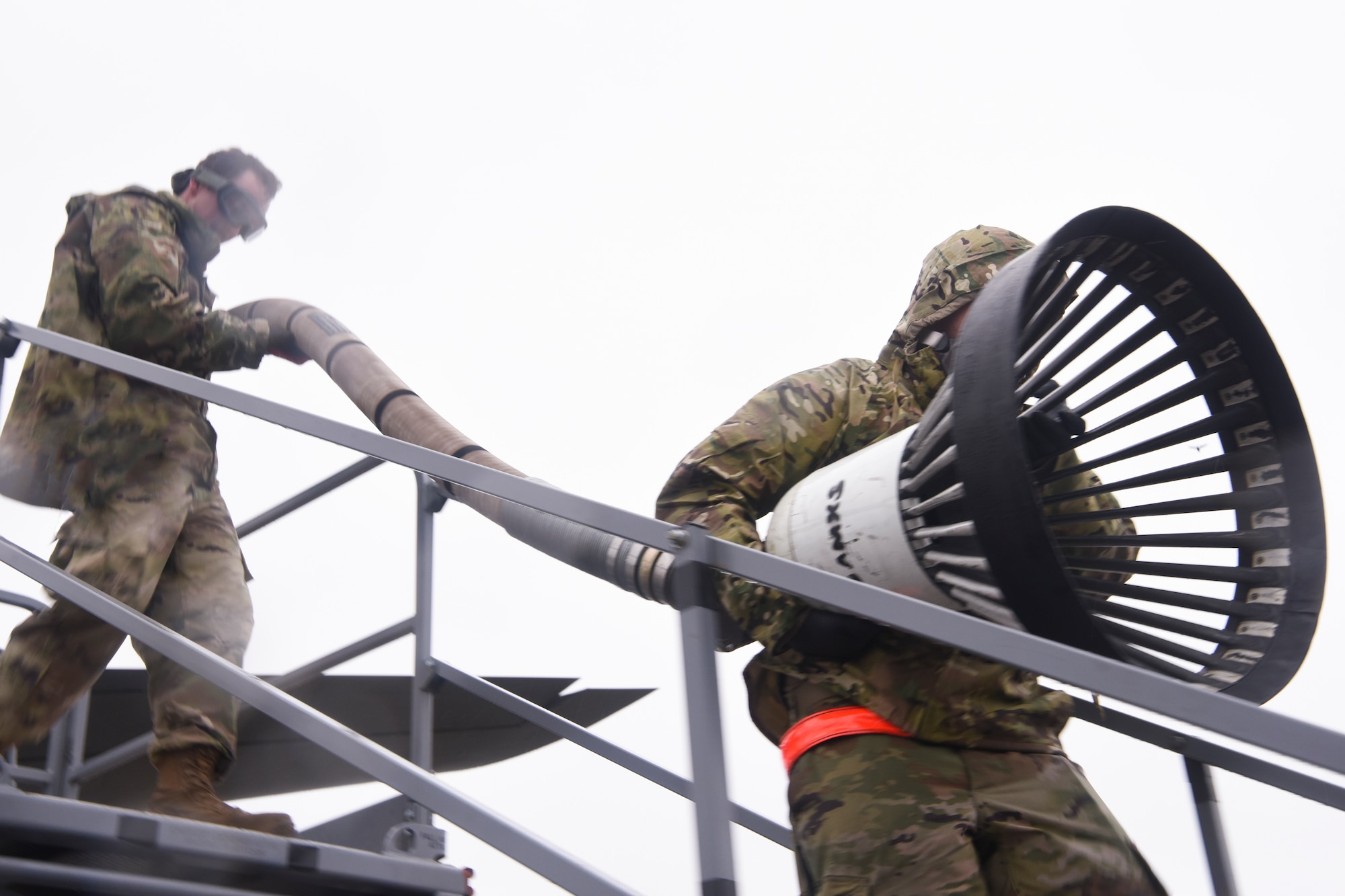 U.S. Air Force Staff Sgt. Elijah Ward, left, 100th Aircraft Maintenance Squadron crew chief, and Airman 1st Class Julian Nailing, right, 100th AMXS crew chief, carry the drogue down from a KC-135 Stratotanker aircraft at Royal Air Force Mildenhall, England, Oct. 29, 2020. After the drogue is removed from the aircraft, it is cleaned and stored.  (U.S. Air Force photo by Airman 1st Class David Busby)