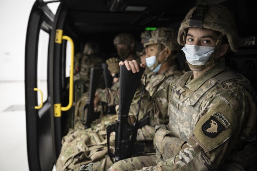 Soldiers sit in a helicopter.