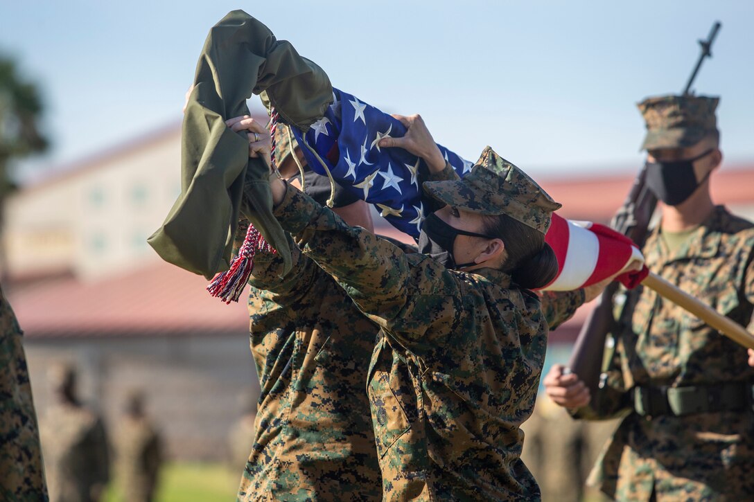 Marines uncase an American flag before a ceremony.