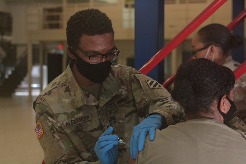 A combat medic administers a flu shot to a soldier.