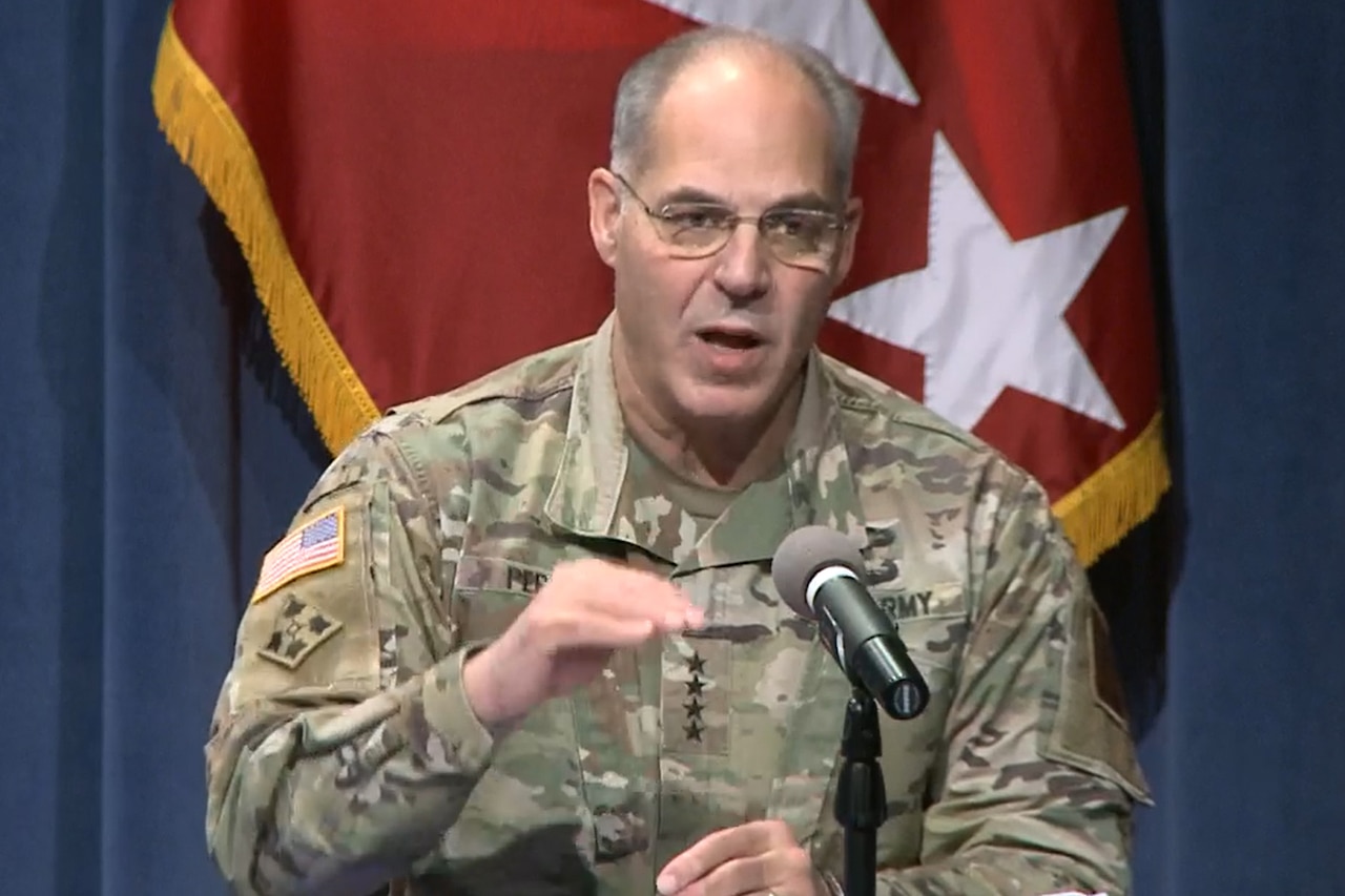 A man in a military uniform speaks into a microphone.