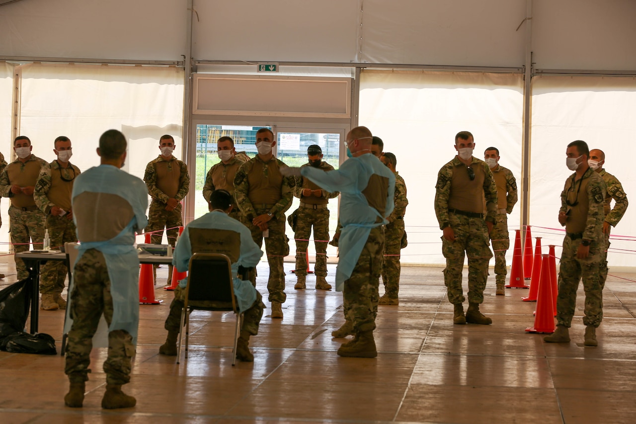 Soldiers wearing face masks wait at a COVID screening station.
