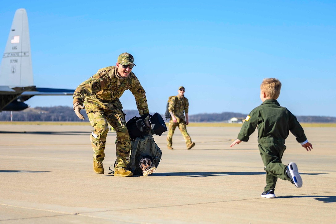 A child runs toward an airman on a flightline.