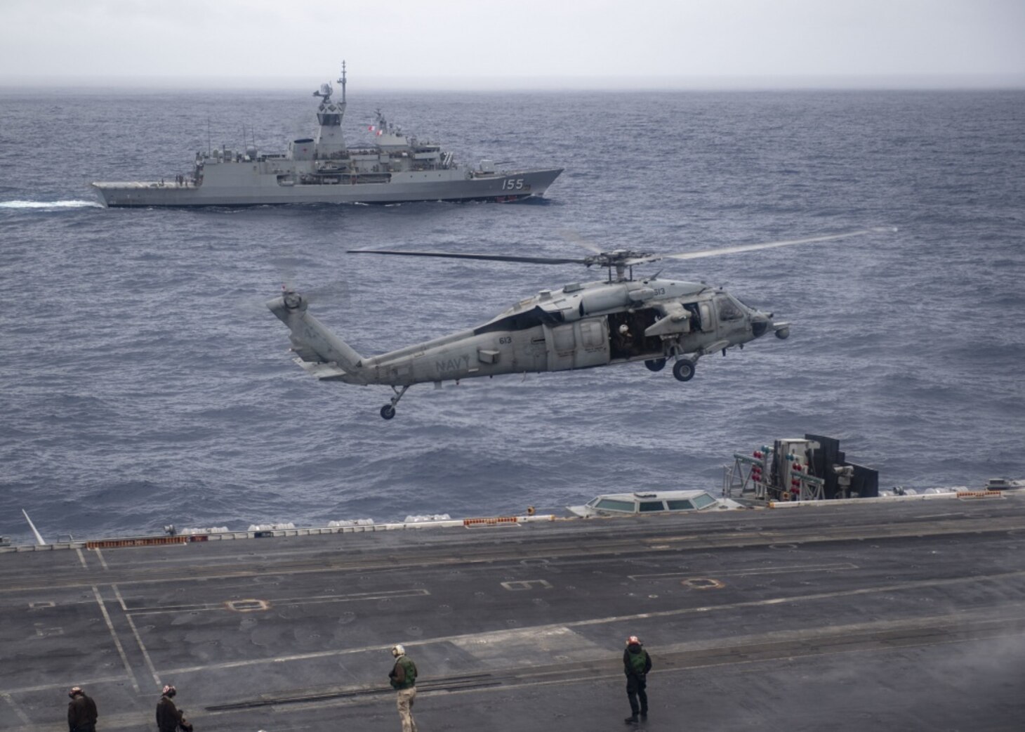 INDIAN OCEAN (Nov. 23, 2020) The Royal Australian Navy Anzac-class frigate HMAS Ballarat (FFH 155) steams alongside the aircraft carrier USS Nimitz (CVN 68) as an MH-60S Sea Hawk helicopter, from the "Screamin’ Indians" of Helicopter Sea Combat Squadron (HSC) 6, descends on the flight deck of the Nimitz. Nimitz, the flagship of Carrier Strike Group 11, is deployed conducting maritime security operations and theater security cooperation efforts.