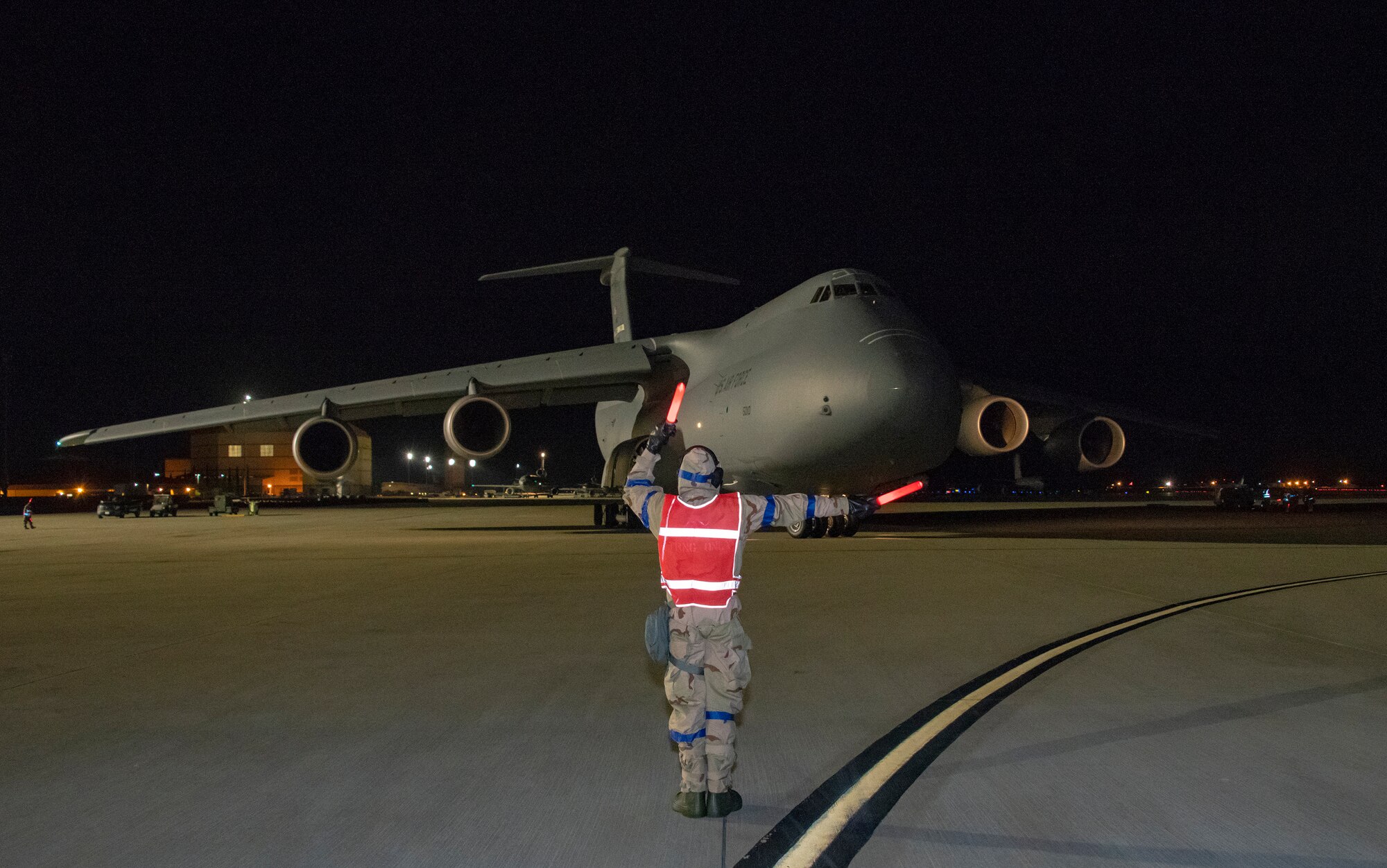 U.S. Air Force Airman 1st Class Ryan Massey, 60th Aircraft Maintenance Squadron crew chief, marshals a C-5M Super Galaxy during an exercise Nov. 18, 2020, at Travis Air Force Base, California. Airmen at Travis AFB participate in readiness exercises to ensure they can operate in contested environments. (U.S. Air Force photo by Heide Couch)