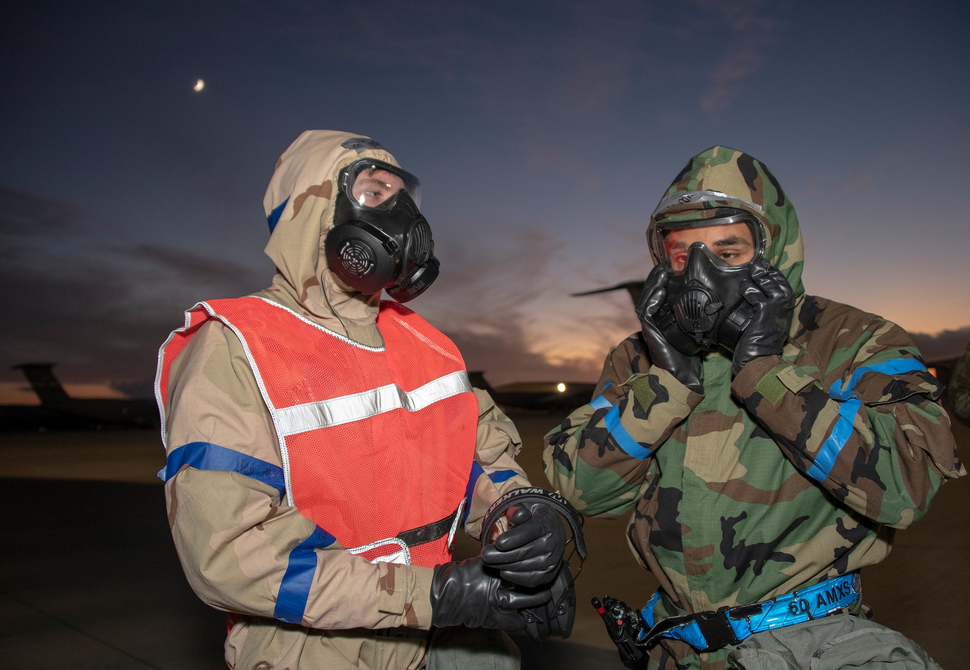 U.S. Air Force Airman 1st Class Ryan Massey, right, and Airman 1st Class Evan Conrad, both 60th Aircraft Maintenance Squadron C-5 crew chiefs, check their mission oriented protective posture gear while participating in an exercise Nov. 18, 2020, at Travis Air Force Base, California. Airmen at Travis AFB participate in readiness exercises to ensure they can operate in contested environments. (U.S. Air Force photo by Heide Couch)
