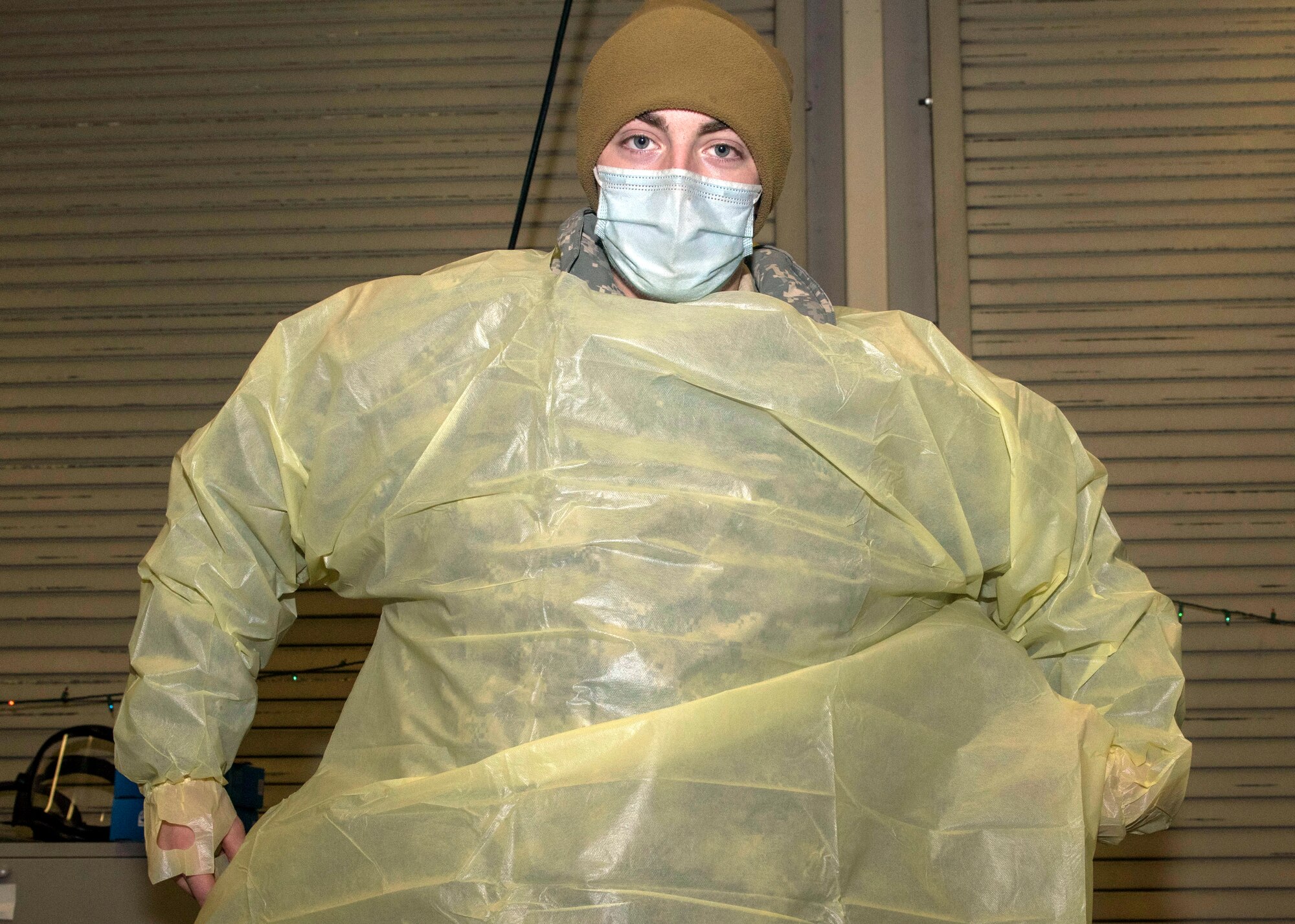 U.S. Army Pvt. Daniel Murtagh, a combat medic specialist assigned to the 1st Squadron, 40th Cavalry Regiment (Airborne), 4th Infantry Brigade Combat Team (Airborne), 25th Infantry Division, U.S. Army Alaska, dons personal protective equipment prior to testing patients for COVID-19 at Joint Base Elmendorf-Richardson, Alaska, Nov. 20, 2020. The 673d MDG stood-up a drive-thru testing clinic to offer a fast, safe way to provide testing to base personnel and their dependents.