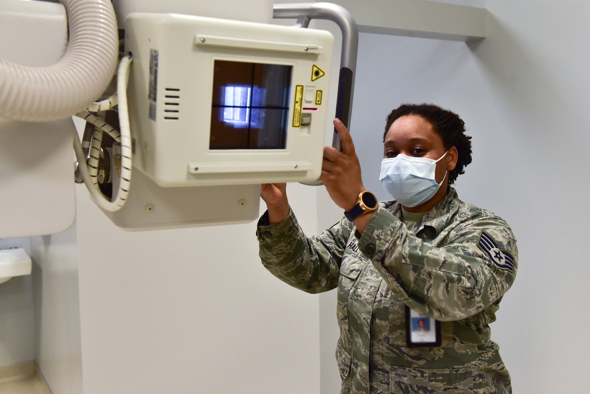 A woman stands wearing a mask while using a imaging machine