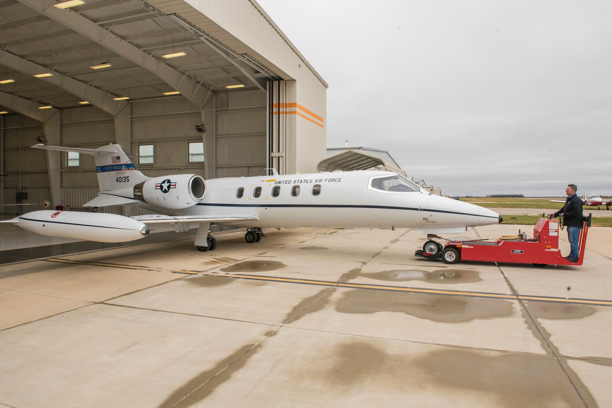 An aircraft technician from AVCON Industries tows the newly-modified C-21A out of a hangar for a final test flight with Air Force pilots Nov. 10, 2020, at Newton City Airport, Kansas. Stabilizing fins added to the aircraft will allow for smoother travel, take-off and landing for the C-21A airlift mission. (U.S. Air Force photo by Staff Sgt. Nathan Eckert)