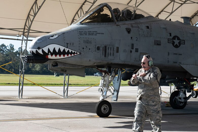 Retired crew chief marshals aircraft.