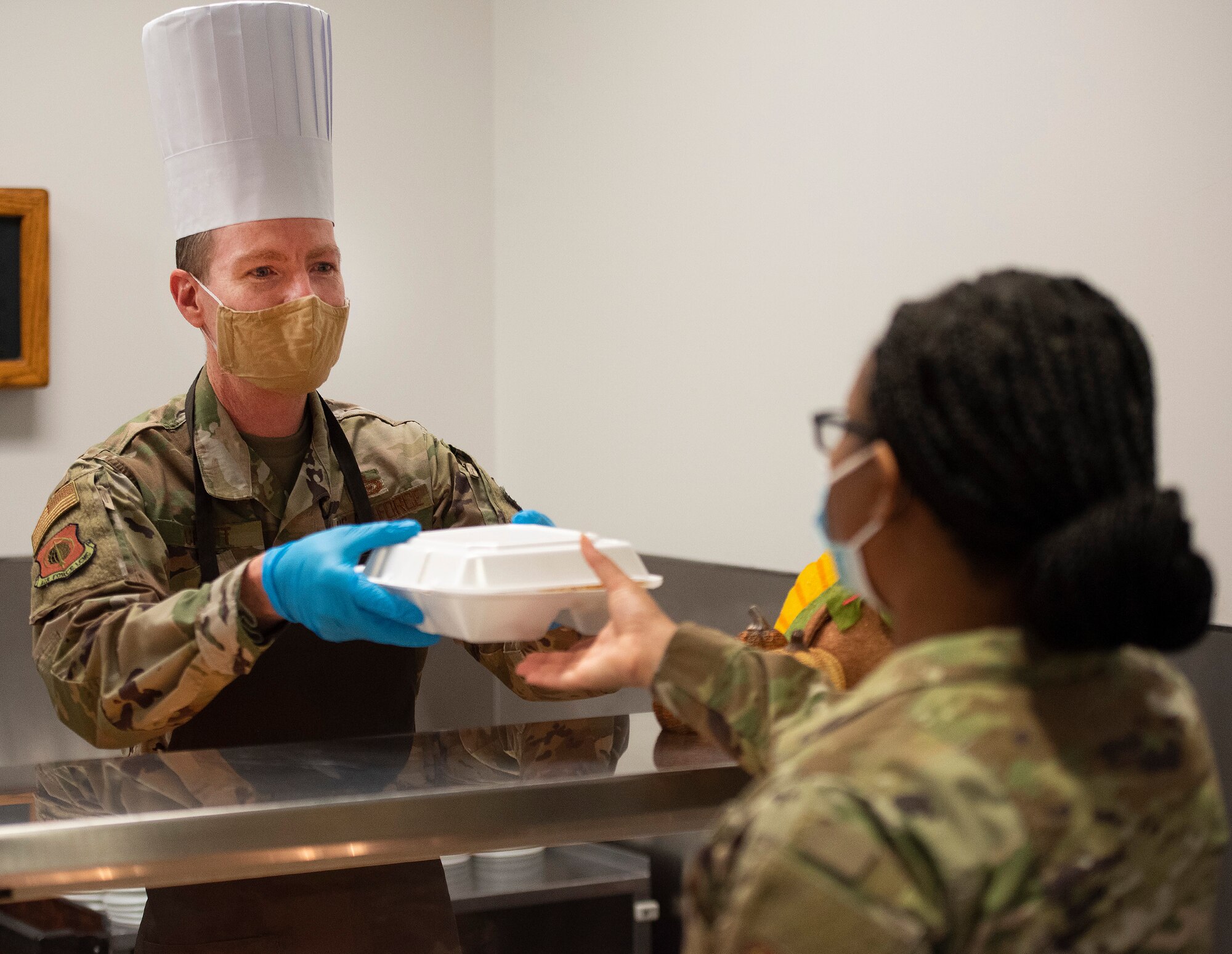 Chief Master Sgt. Troie A. Croft, Air Force Life Cycle Management Center command chief, hands an Airman a Thanksgiving dinner