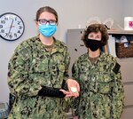 Capt. Lisa Mulligan, Naval Medical Center Portsmouth (NMCP) commanding officer (right), presents a command coin with congratulations to Branch Health Clinic Norfolk’s Lt. Laura Corey for receiving the Navy’s Junior Psychologist of the Year award.