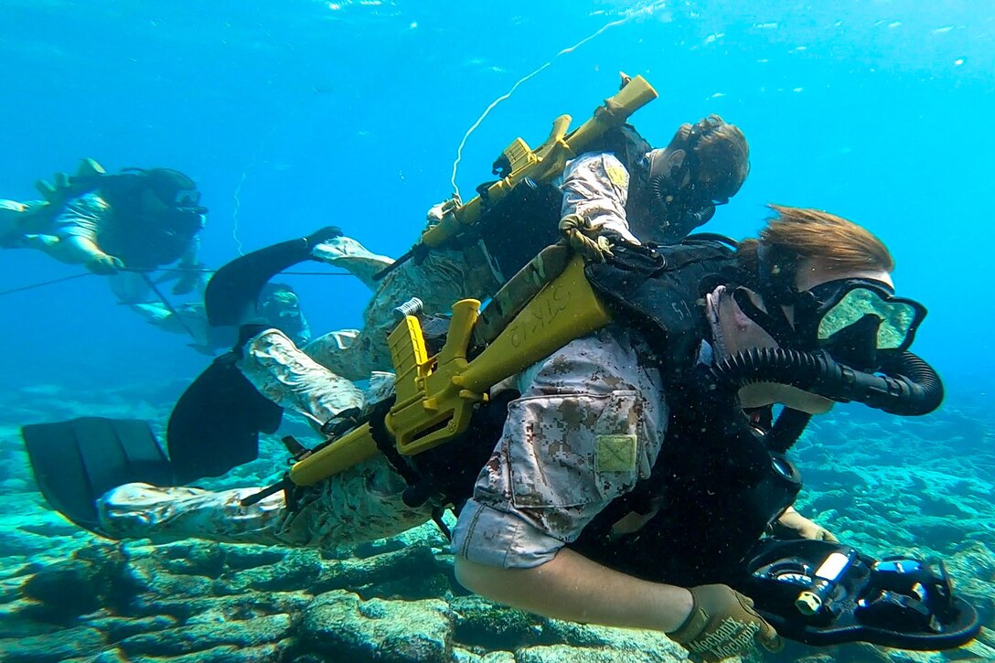 Marines scuba dive in the water.