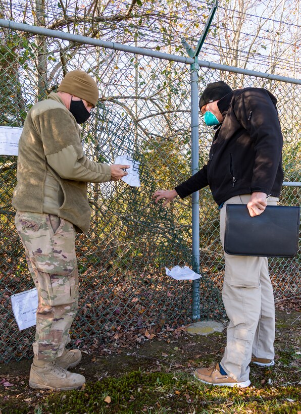 Tech. Sgt. Shawn Hyde, 436th Civil Engineer Squadron horizontal shop noncommissioned officer in charge, and Staff Sgt. Alexander Oelfke, 436th Security Forces Squadron investigator, examine a simulated breach in the base’s perimeter fence Nov. 18, 2020, at Dover Air Force Base, Delaware. The exercise entailed 24-hour operations and consisted of an array of scenarios to test the base’s emergency response capabilities, satisfying multiple annual requirements. (U.S. Air Force photo by Roland Balik)