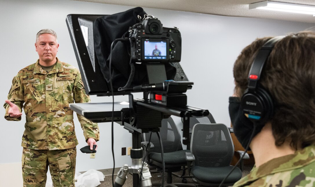 Col. Mike Peeler, 436th Operations Group commander and crisis action team director, reads a mock prepared news release from a teleprompter during the base's force protection exercise Nov. 19, 2020, at Dover Air Force Base, Delaware. On the right, Airman 1st Class Stephani Barge, 436th Airlift Wing public affairs apprentice, records Peeler as he updates the public on the exercise incident. The mock news release was used as a training opportunity for wing leadership to communicate to the media and general population regarding potential real-world occurrences. This aspect of the exercise also shows Dover AFBs commitment to collaboration with local, state and federal agencies. (U.S. Air Force photo by Roland Balik)