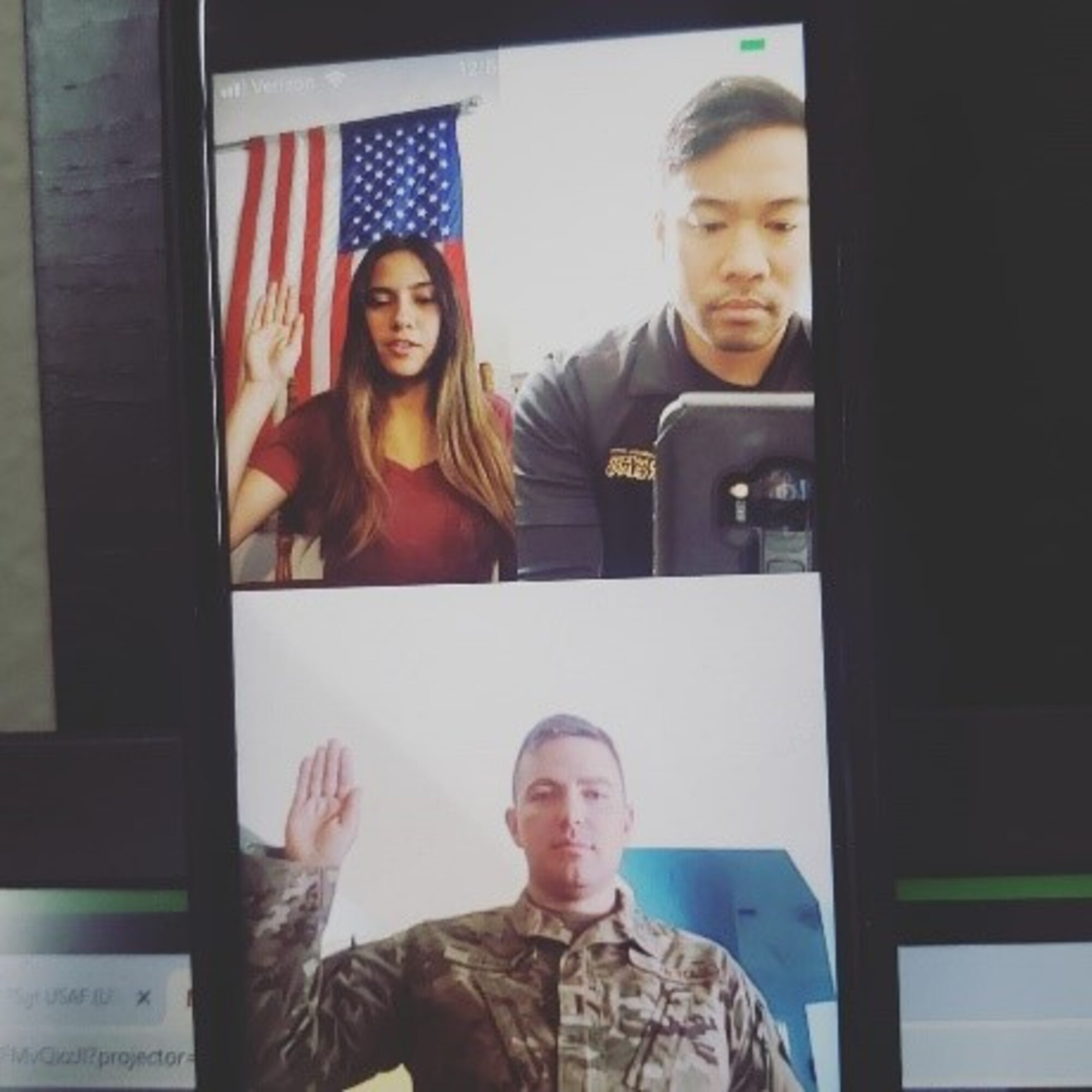 Phone screen showing a man administering the Oath of Enlistment to a lady virtually