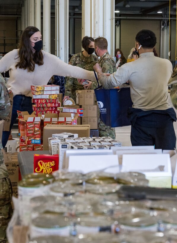 Key spouses, Dover Spouses’ Club members and other volunteers go down an assembly line to fill more than 260 Thanksgiving holiday food bags with nonperishable food items for Team Dover members Nov. 20, 2020, at Dover Air Force Base, Delaware. Food items were placed in reusable thermal grocery bags donated by the Dover Federal Credit Union. Two frozen whole chickens accompanied each food bag given out. (U.S. Air Force photo by Roland Balik)