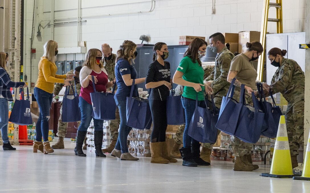 Dover first sergeants, key spouses, Dover Spouses’ Club members and other volunteers form an assembly line to fill more than 260 Thanksgiving holiday food bags with nonperishable food items for Team Dover members Nov. 20, 2020, at Dover Air Force Base, Delaware. Food items were placed in reusable thermal grocery bags donated by the Dover Federal Credit Union. Two frozen whole chickens accompanied each food bag given out. (U.S. Air Force photo by Roland Balik)