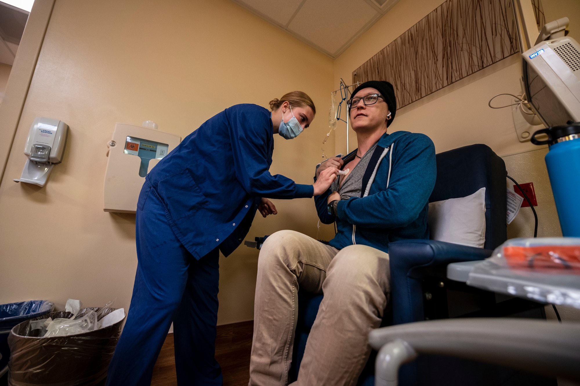 A nurse in blue scrubs cleans a man's chemo-port located on his chest.