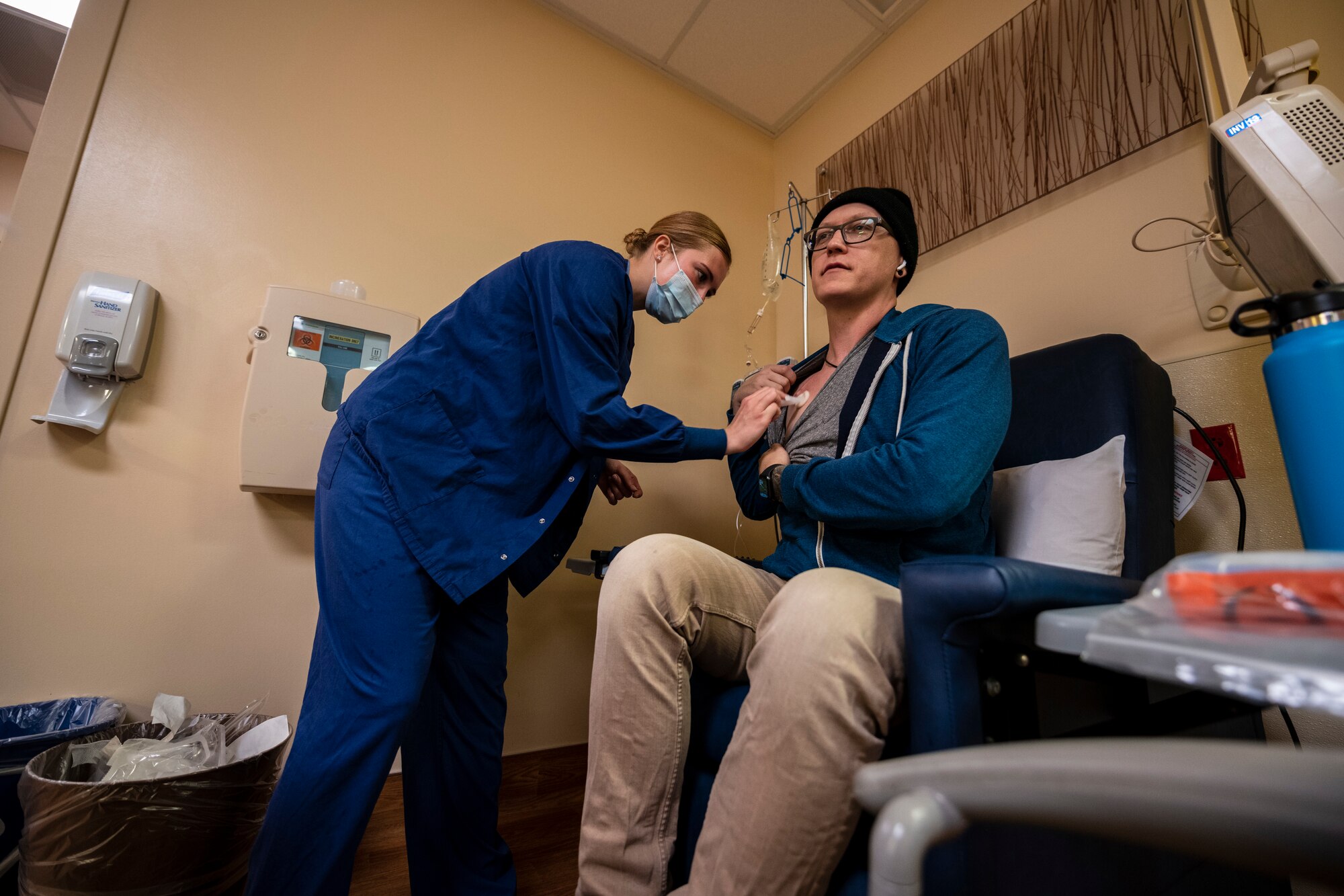 A nurse in blue scrubs cleans a man's chemo-port located on his chest.