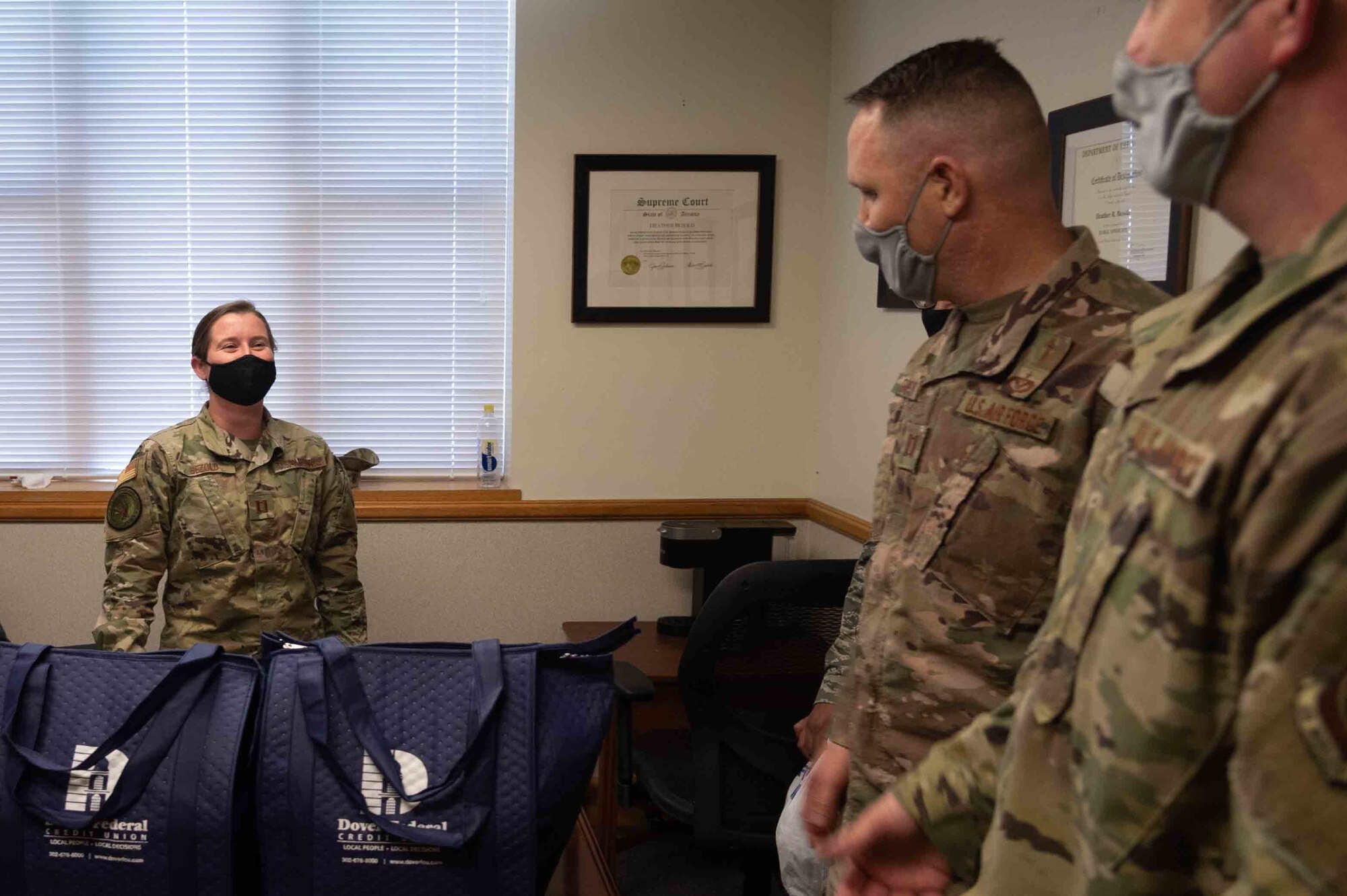 Capt. Heather Bezold, 436th Airlift Wing judge advocate, receives a Thanksgiving holiday food bag from Chaplain (Capt.) Jonathan Dawson, 436th Airlift Wing chaplain and Master Sgt. Tony Otis, 436th Wing Staff Agency first sergeant Nov. 23, 2020, at Dover Air Force Base, Delaware. Dover first sergeants, Key Spouses, Dover Spouses Group and other volunteers helped deliver 260 bags of Thanksgiving dinner kits for Airmen including two whole chickens, canned vegetables and pie ingredients. (U.S. Air Force photo by Airman 1st Class Faith Schaefer)