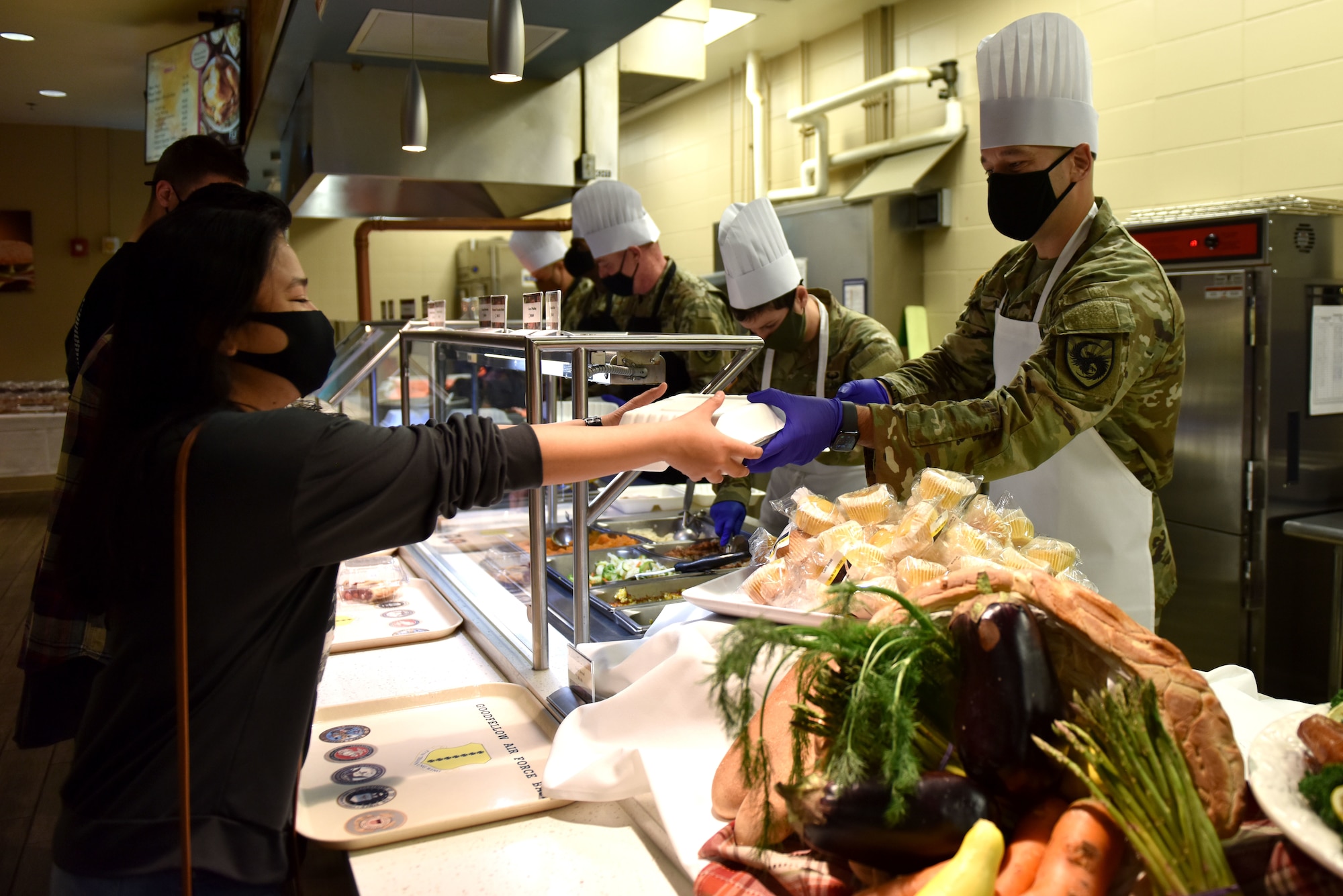A volunteer hands a Goodfellow member their food at the Thanksgiving meal in the Western Winds Dining Facility on Goodfellow Air Force Base, Texas, Nov. 26, 2020. Members had the choice of roast beef, turkey or ham accompanied by sides. (U.S. Air Force photo by Staff Sgt. Seraiah Wolf)