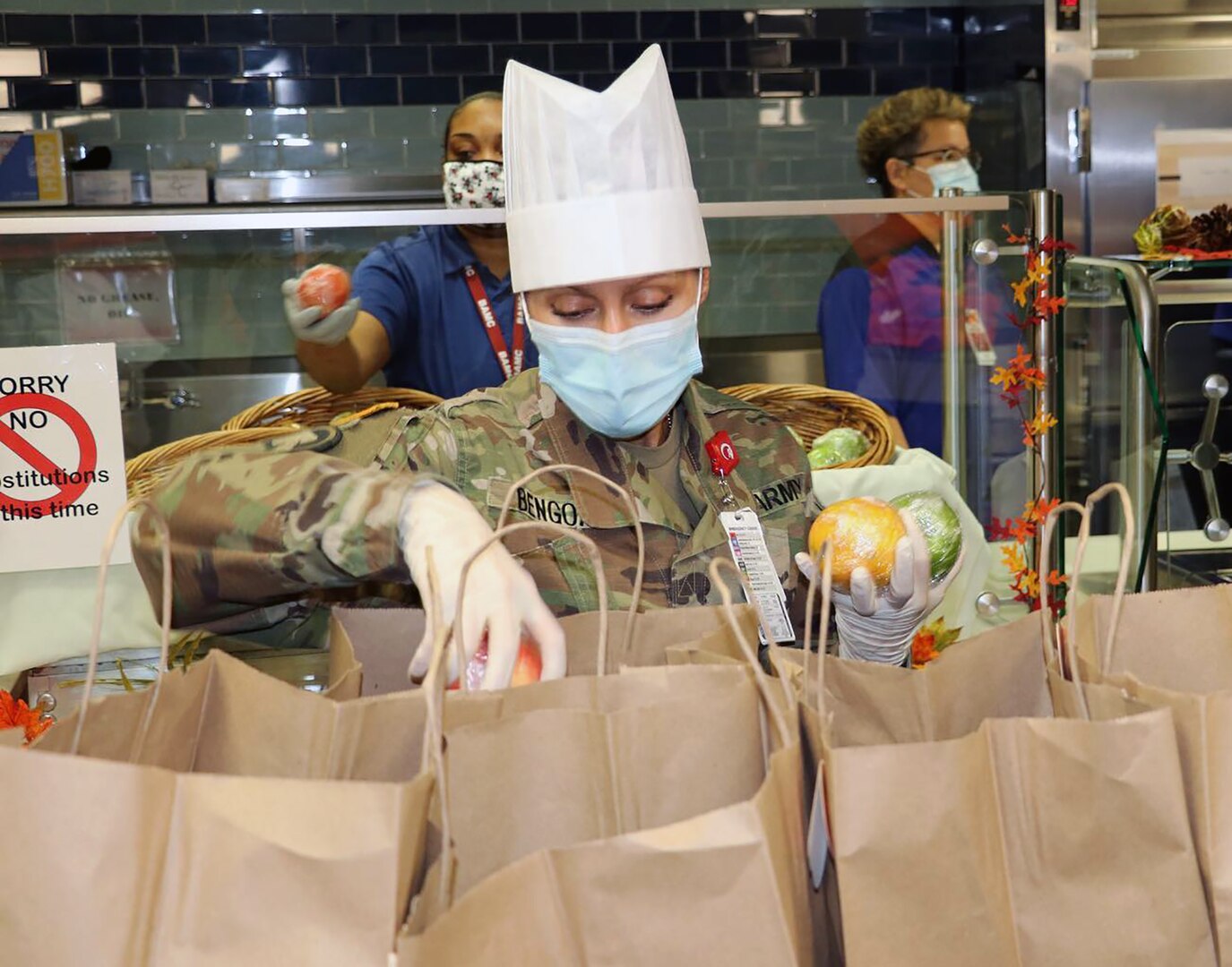 Army Sgt. 1st Class, Maité Bengoa, Enlisted Advisor to the Deputy Commander for Health and Readiness, Brooke Army Medical Center, fills a five-bag fruit order in the serving line for a staff member as part of their pre-packaged Thanksgiving Day meal Nov. 26.