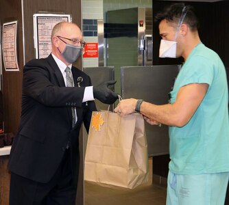 Dr. Evan Renz, Deputy to the Commander for Quality and Safety, Brooke Army Medical Center, hands a pre-packaged Thanksgiving Day meal to a staff member Nov. 26.