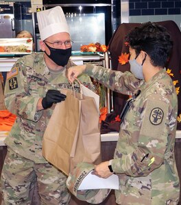 Army Col. Daniel Thompson, Chief Nursing Officer, Brooke Army Medical Center, hands a pre-packaged Thanksgiving Day meal to a staff member Nov. 26.