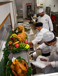 Cmdr. Terry McNamara and Command Master Chief Derek Mullenhour, help food service specialists prepare Thanksgiving to-go meals at Fleet Activities Yokosuka.