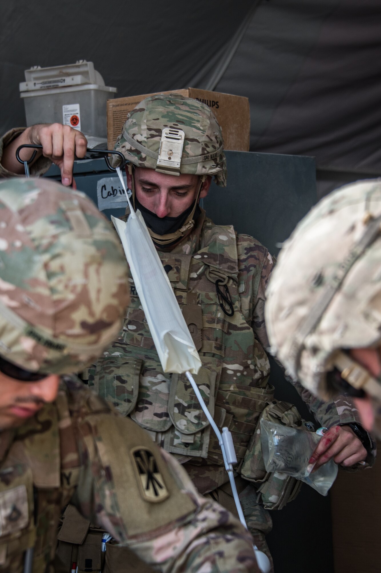 a soldier sets up an IV bag