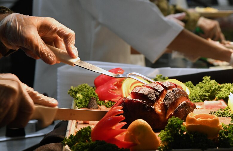 U.S. Air Force Col. Chance Geray, 81st Training Group commander, slices a ham inside the Azalea Dining Facility at Keesler Air Force Base, Mississippi, Nov. 26, 2020. It is tradition at Keesler for commanders, first sergeants and superintendents to serve a Thanksgiving meal at the dining facility to technical training and permanent party Airmen who are not able to go home for the holiday. (U.S. Air Force photo by Kemberly Groue)
