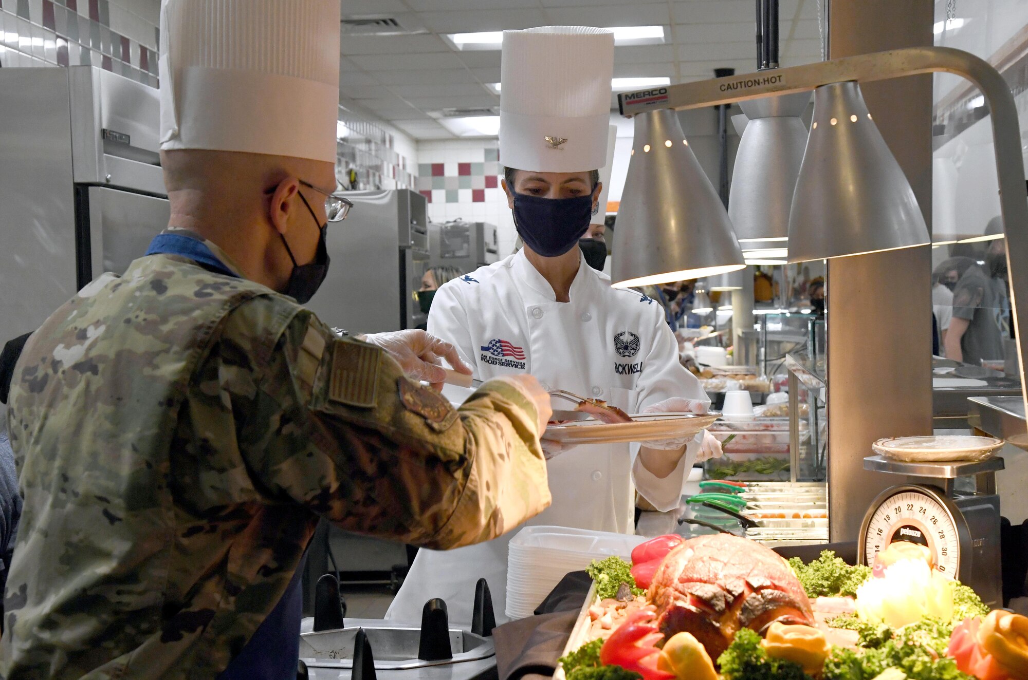 U.S. Air Force Col. Chance Geray, 81st Training Group commander, places a piece of ham on a plate for Col. Heather Blackwell, 81st Training Wing commander, inside the Azalea Dining Facility at Keesler Air Force Base, Mississippi, Nov. 26, 2020. It is tradition at Keesler for commanders, first sergeants and superintendents to serve a Thanksgiving meal at the dining facility to technical training and permanent party Airmen who are not able to go home for the holiday. (U.S. Air Force photo by Kemberly Groue)
