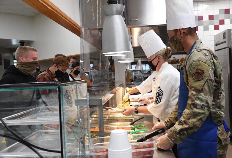 U.S. Air Force Chief Master Sgt. Sarah Esparza, 81st Training Wing command chief, and Senior Master Sgt. Jason Strickland, 81st Medical Support Squadron first sergeant, serve lunch to 81st Training Group students inside the Azalea Dining Facility at Keesler Air Force Base, Mississippi, Nov. 26, 2020. It is tradition at Keesler for commanders, first sergeants and superintendents to serve a Thanksgiving meal at the dining facility to technical training and permanent party Airmen who are not able to go home for the holiday. (U.S. Air Force photo by Kemberly Groue)