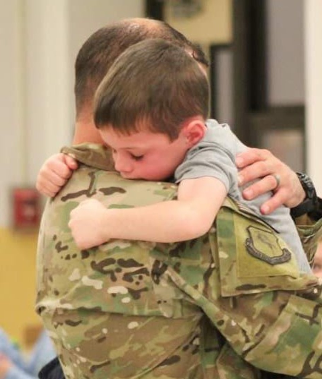 A small boy hugs his father.