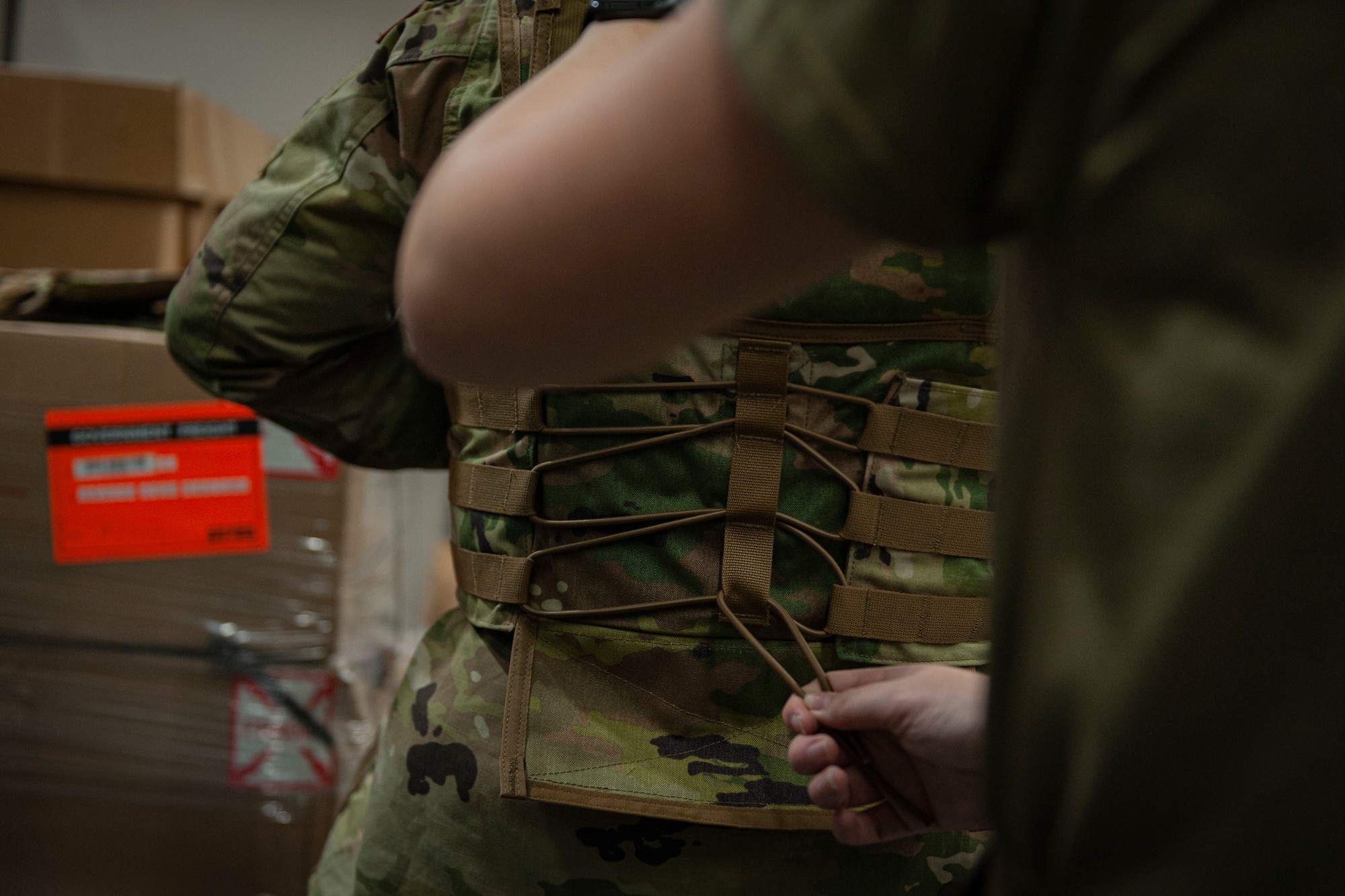 Photo of an Airman adjusting a corset on a vest