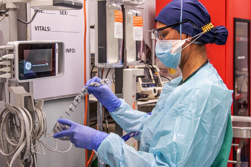 A woman wearing personal protective equipment prepares medical equipment for incoming COVID-19 patients.