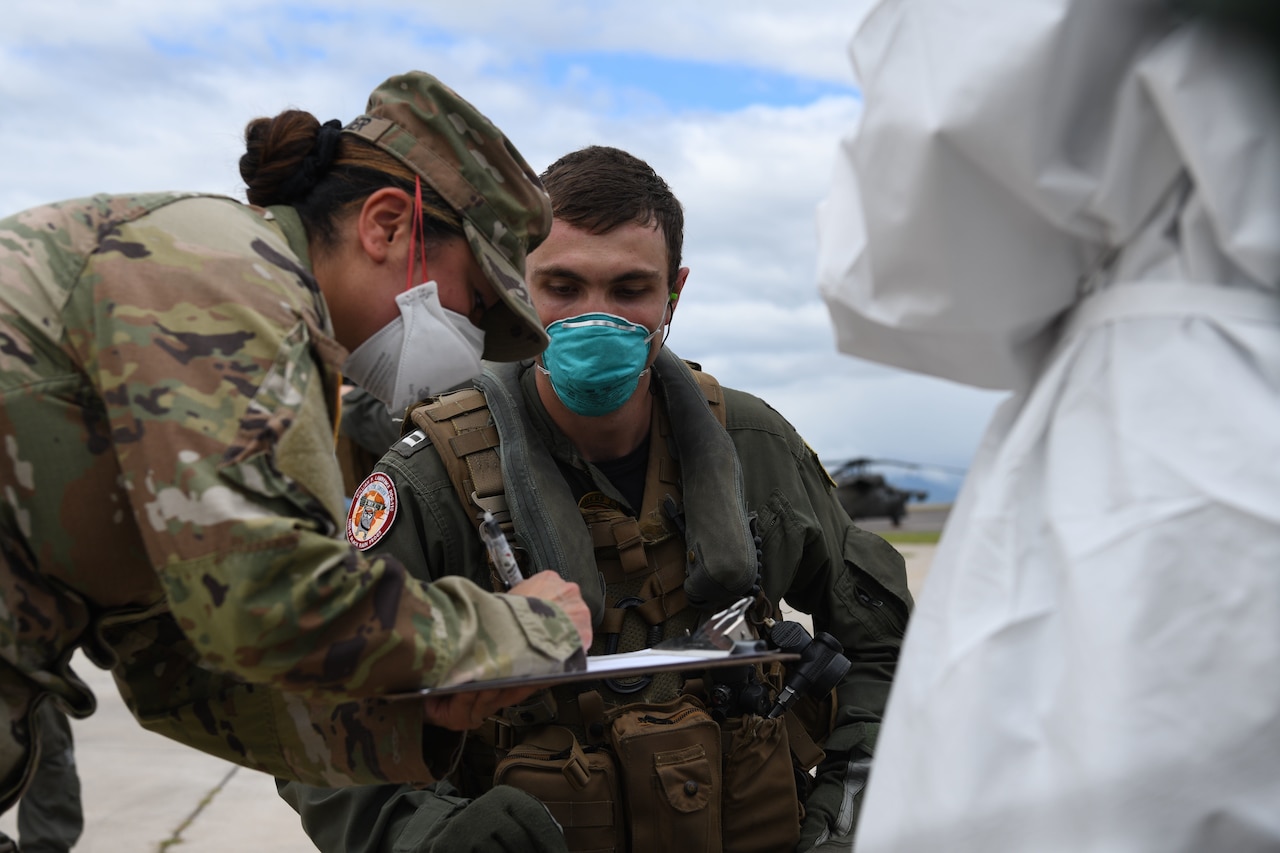 A pilot interacts with a person in full personal protective equipment.