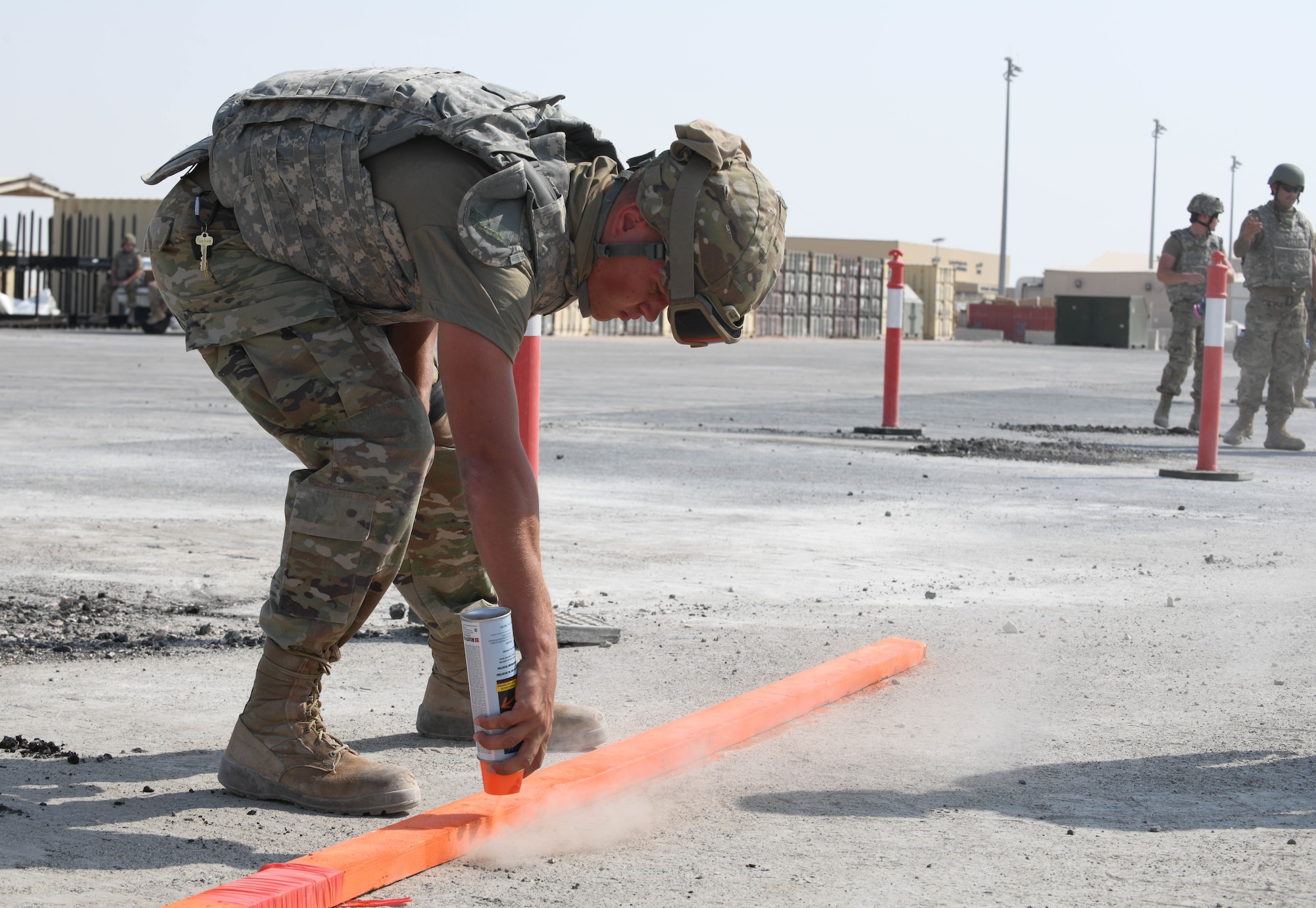 Airman 1st Class Cole Weber, a pavement construction equipment apprentice assigned to the 379th Expeditionary Civil Engineer Squadron, uses a piece of wood to spray paint boundaries around a crater during rapid airfield damage repair training Nov. 18, 2020, at Al Udeid Air Base, Qatar. 379th ECES Airmen came together to conduct RADR training, which prepares them to make expeditious repairs to an airfield should it be attacked, bringing it back to operational status. (U.S. Air Force photo by Staff Sgt. Kayla White)