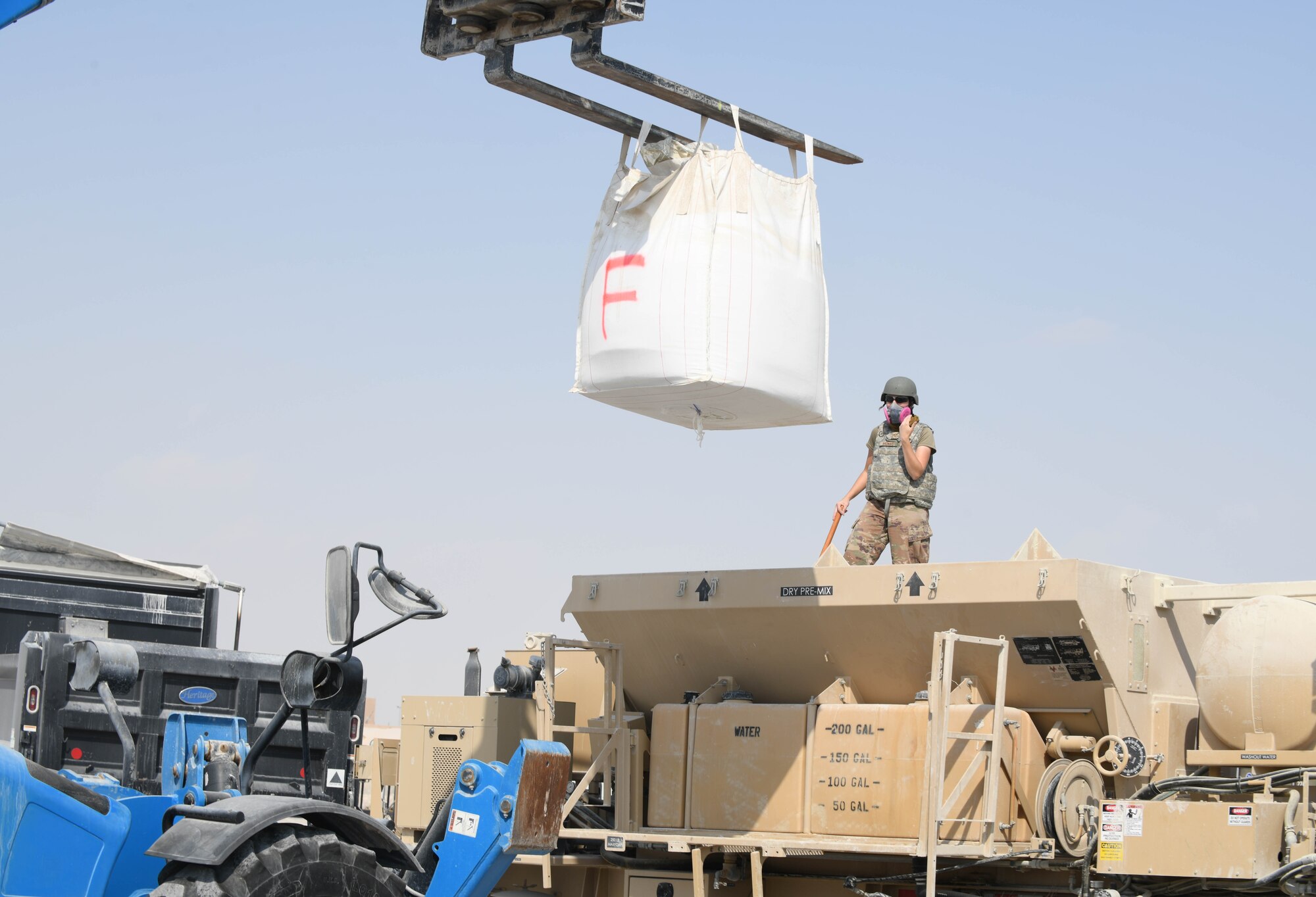 U.S. Air Force Staff Sgt. Jessica Vadnais, with the 379th Expeditionary Civil Engineer Squadron, guides a telescopic handler carrying an industrial-sized bag of concrete toward a cement mixer at Al Udeid Air Base, Qatar, Nov. 18, 2020. The 379th ECES Airmen repaired craters in a mock airfield as part of a rapid airfield damage repair training exercise, which helped prepare them to efficiently and expeditiously restore a damaged airfield to operational status. (U.S. Air Force photo by Staff Sgt. Kayla White)