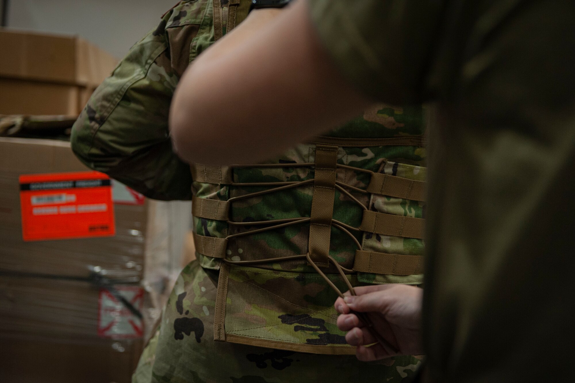 Photo of an Airman adjusting a corset on a vest