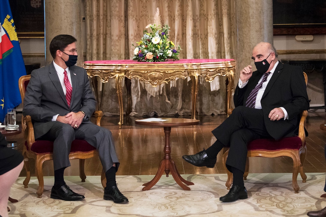 Two men, seated, are in conversation.