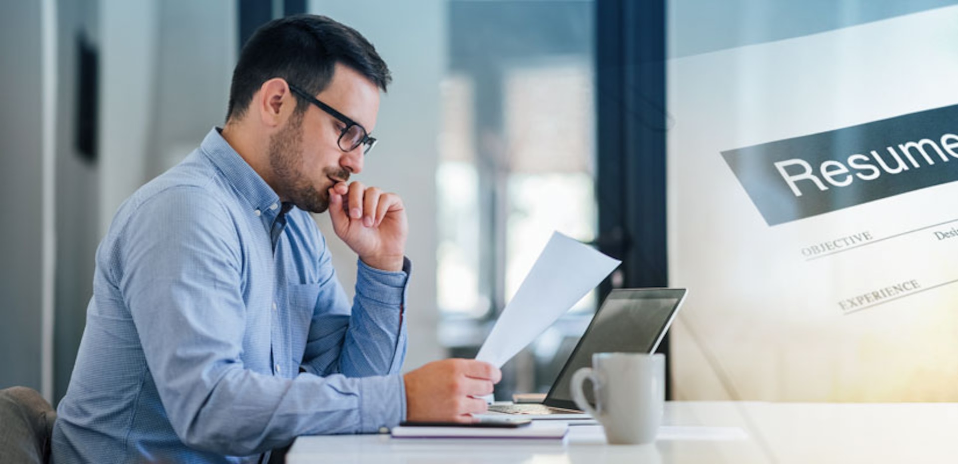 Man reviewing documents while working on his laptop.