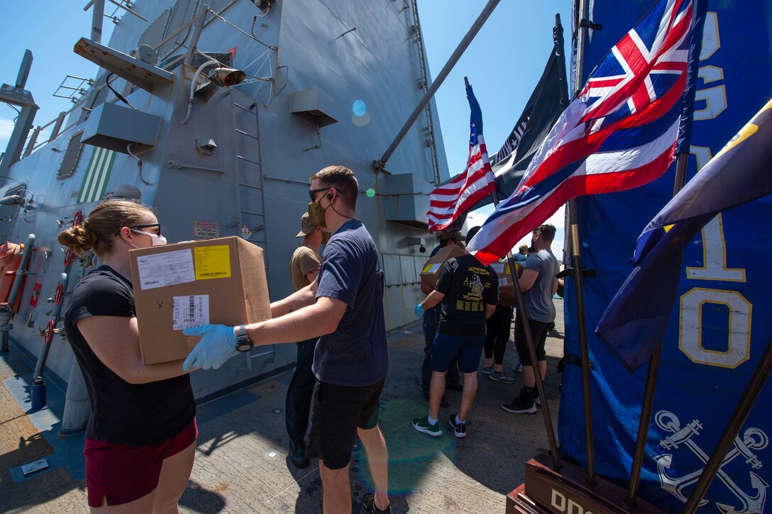 A man and woman load a box of supplies onto a ship.