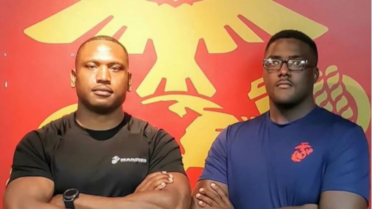 Two men in T-shirts look at the camera with their arms crossed.
