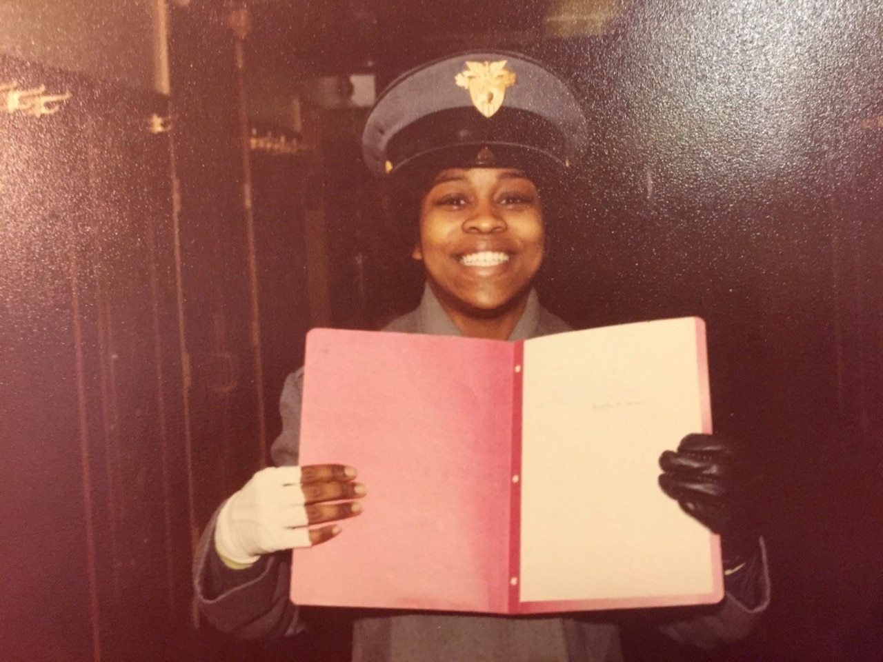 A woman in military uniform holds up a notebook.