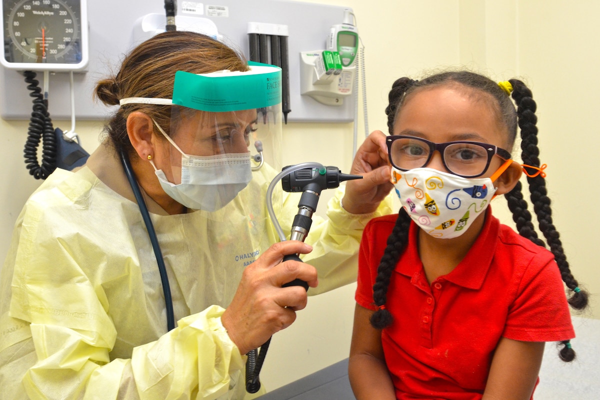 A young child gets an ear exam from a doctor.