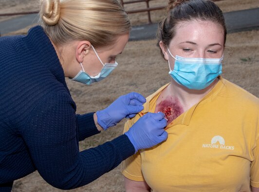 U.S. Air Force Master Sgt. Alissa Leviskia, left, 60th Inpatient Squadron hyperbaric flight chief, applies a simulated gunshot wound on Senior Airman Katie Bean, 60th Aerial Port Squadron fleet services, prior to a base exercise Sept. 24, 2020, at Travis Air Force Base, California. The exercise was designed to evaluate the training, readiness and capability of Travis first responders in order to effectively respond to active shooter threats to the installation. (U.S. Air Force photo by Heide Couch)